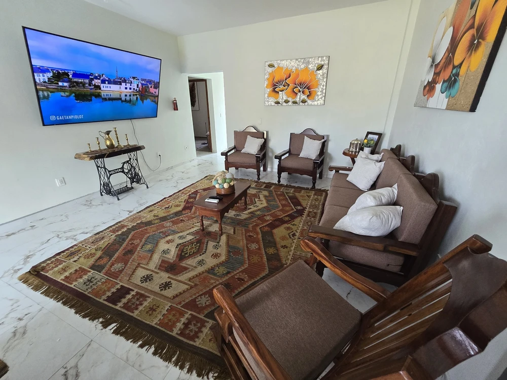 Sala de Casa de los Xolos, con televisión, sillones de madera y alfombra.